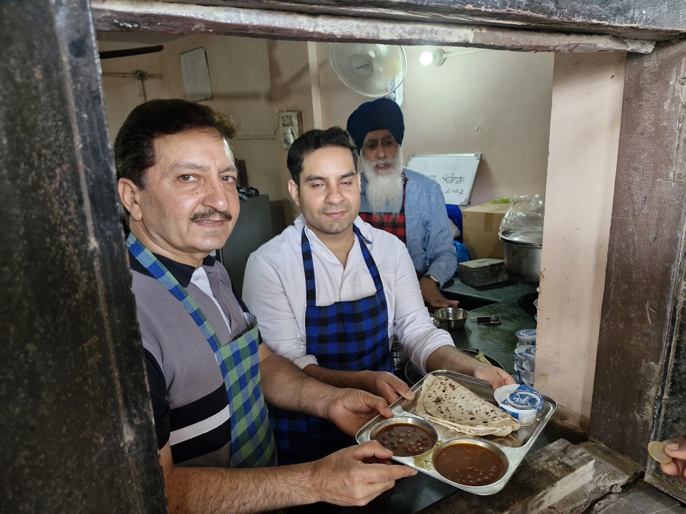 Kitchen volunteers handing a tray of food through the serving window