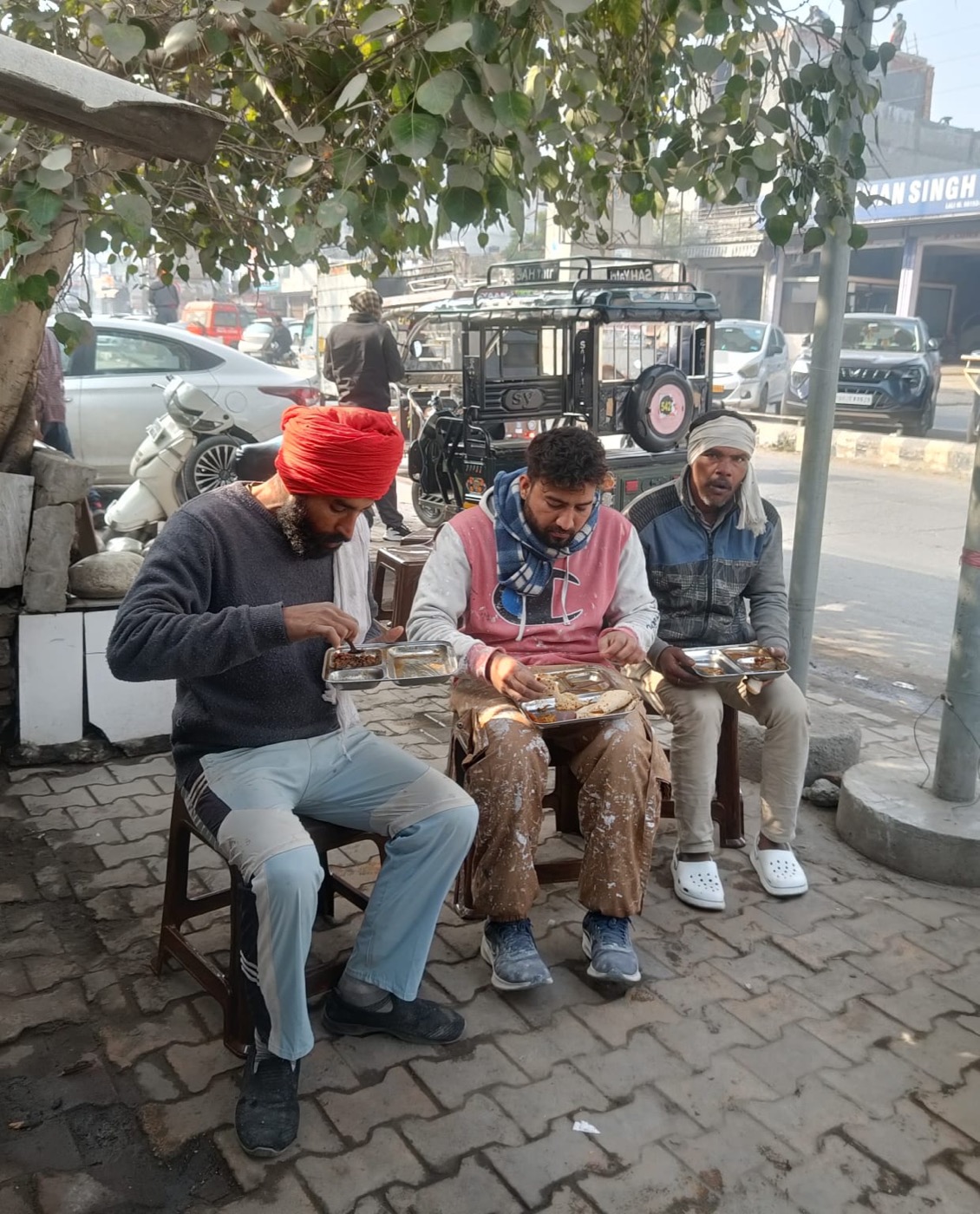 A group sharing food under a tree near the kitchen